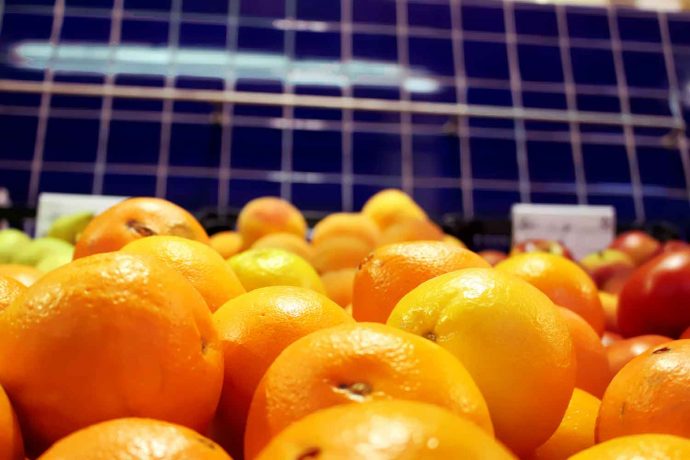 Foto Obst auf Markt in Spanien mit Orangen, Farben orange rot gelb blau mit Fliesen im Hintergrund