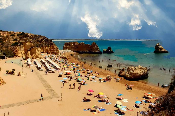 Foto Portugal Felsen Algarve Dona Ana Strand im Hintergrund Meia Preia Strand, Farben blau, türkis und braun, Himmel, Meerwasser,Sand, Kumulus Wolken