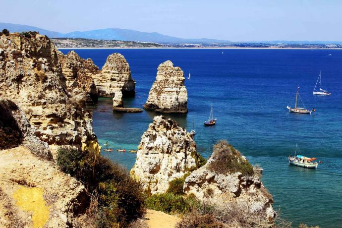 Foto Portugal Felsen Algarve mit Booten Hintergrund Strand Meia Preia, Farben blau, türkis und braun