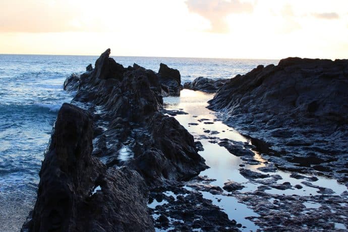 Foto Lavafelsen im Meer auf Lanzarote mit Kumuluswolken blau schwarz